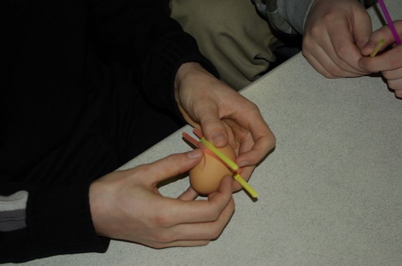 two people are using pencils to make a hole in an egg