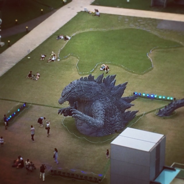 an overhead view of a sculpture of godzilla on a green area next to a building