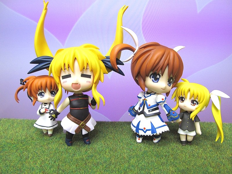 a group of anime style dolls sitting on a grass covered field