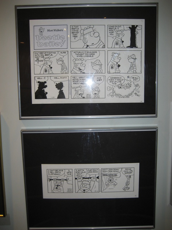 two black frames with cartoon strip panels hanging on wall