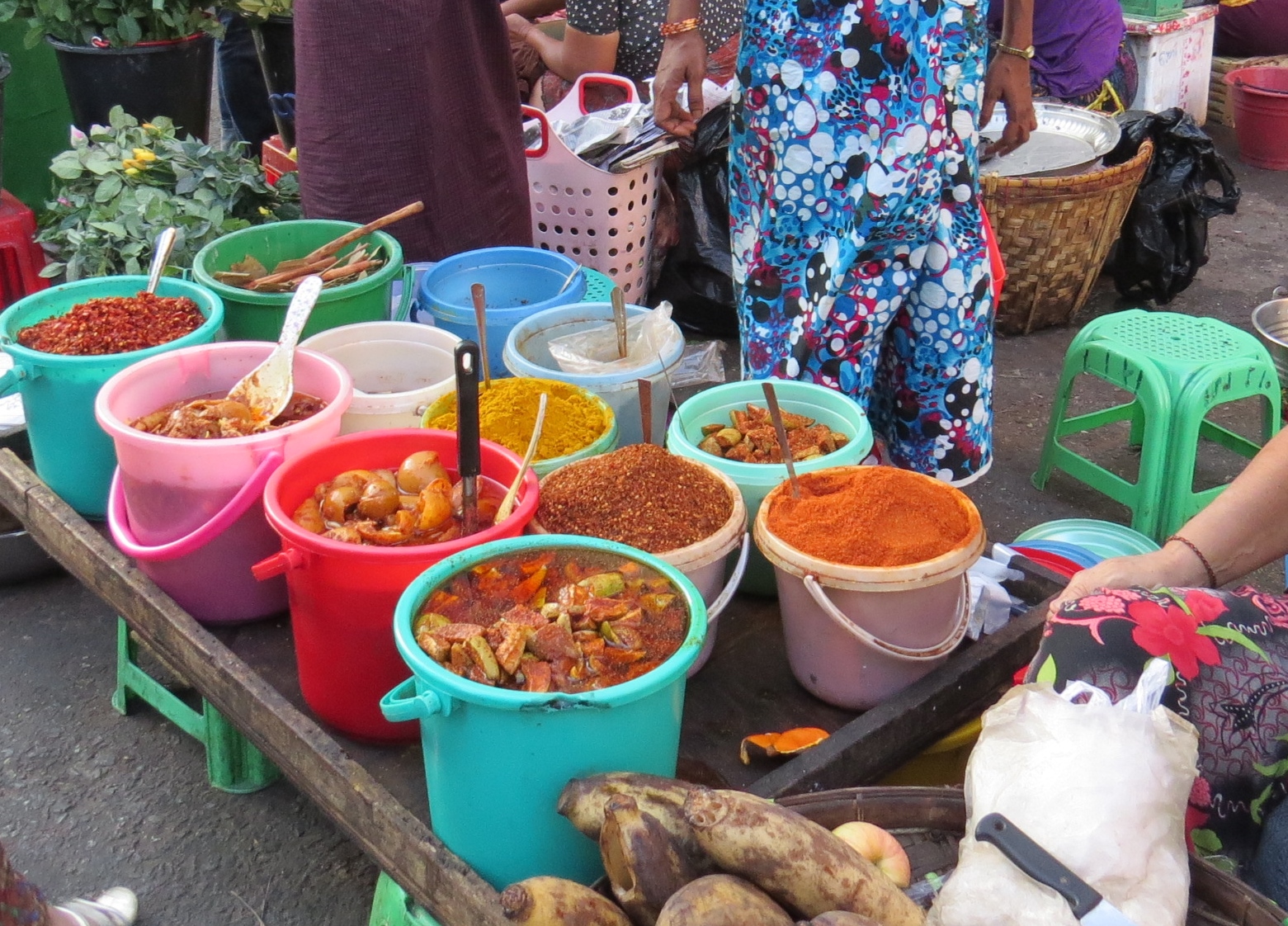 a street vendor stands behind several buckets of different types of food