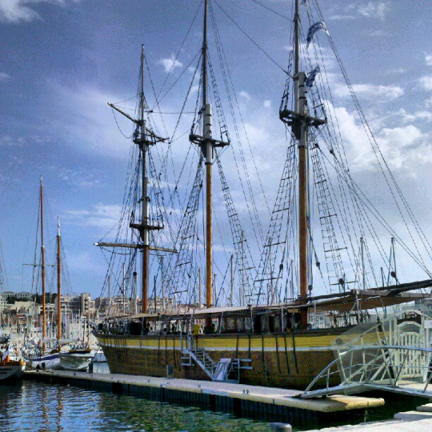 the wooden masted boat is moored at the dock