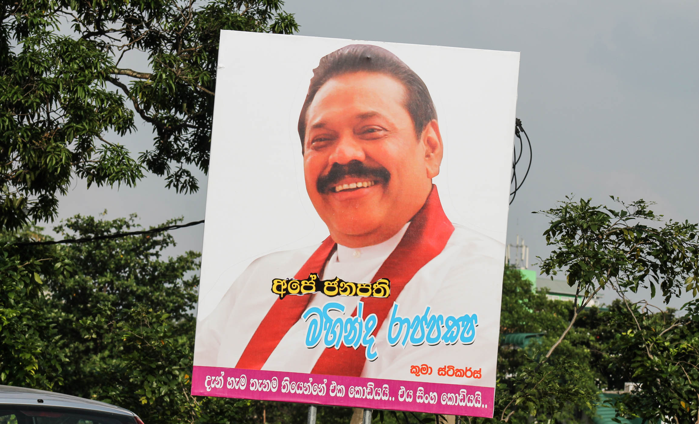 large billboard about a smiling man with trees in the background