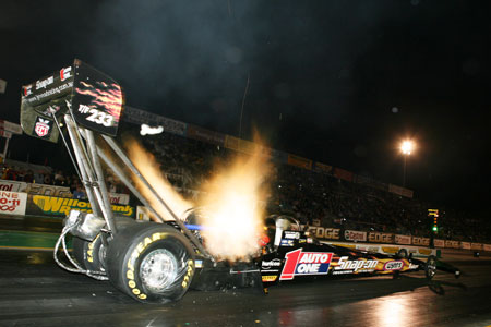 a pit - type car spins around its wheels on a track at night