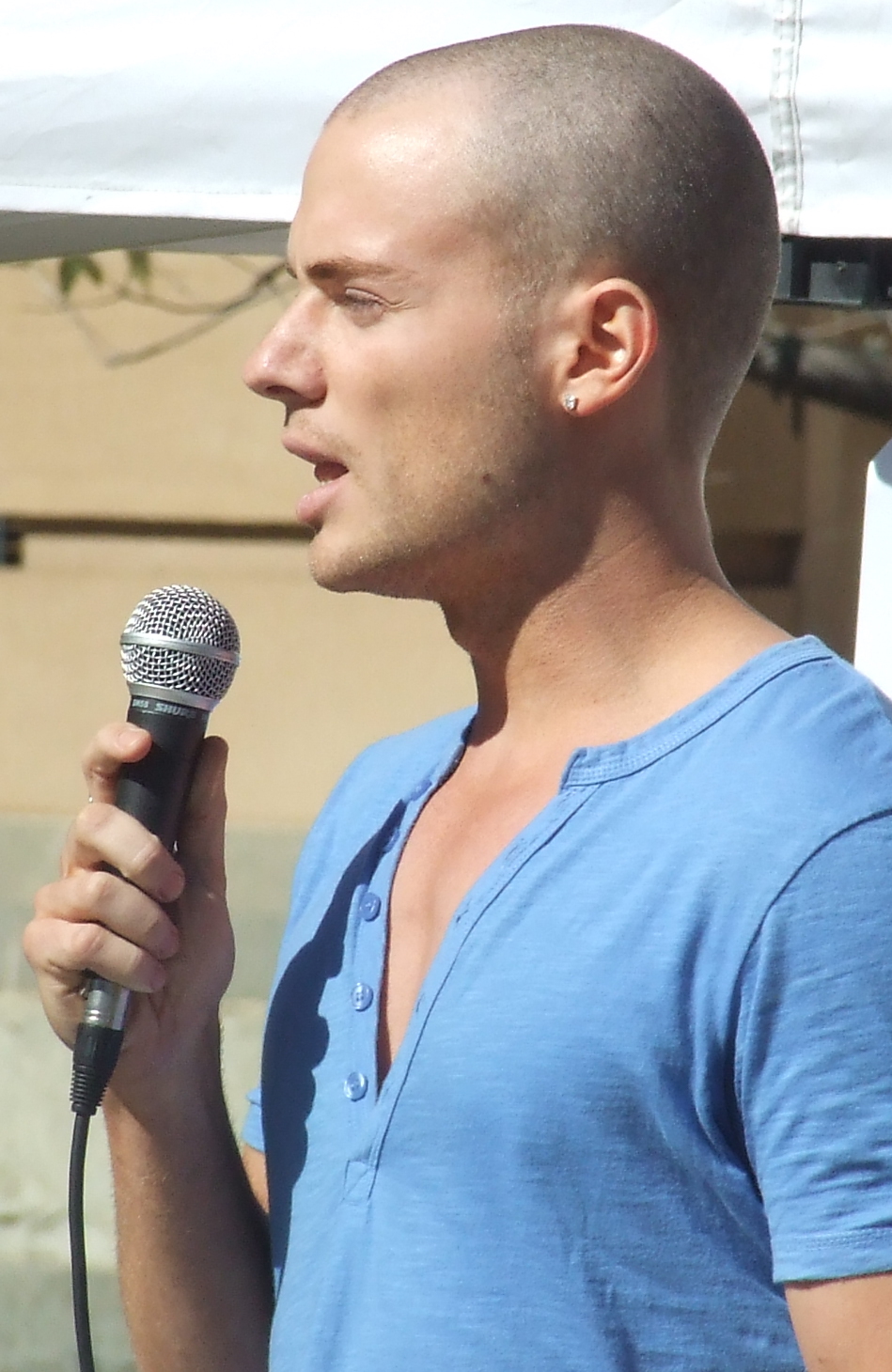 a bald man is holding a microphone at an outdoor event