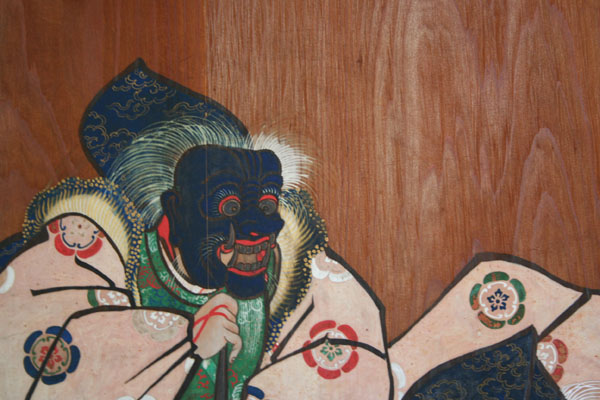 an oriental painting is on display in front of a wooden wall