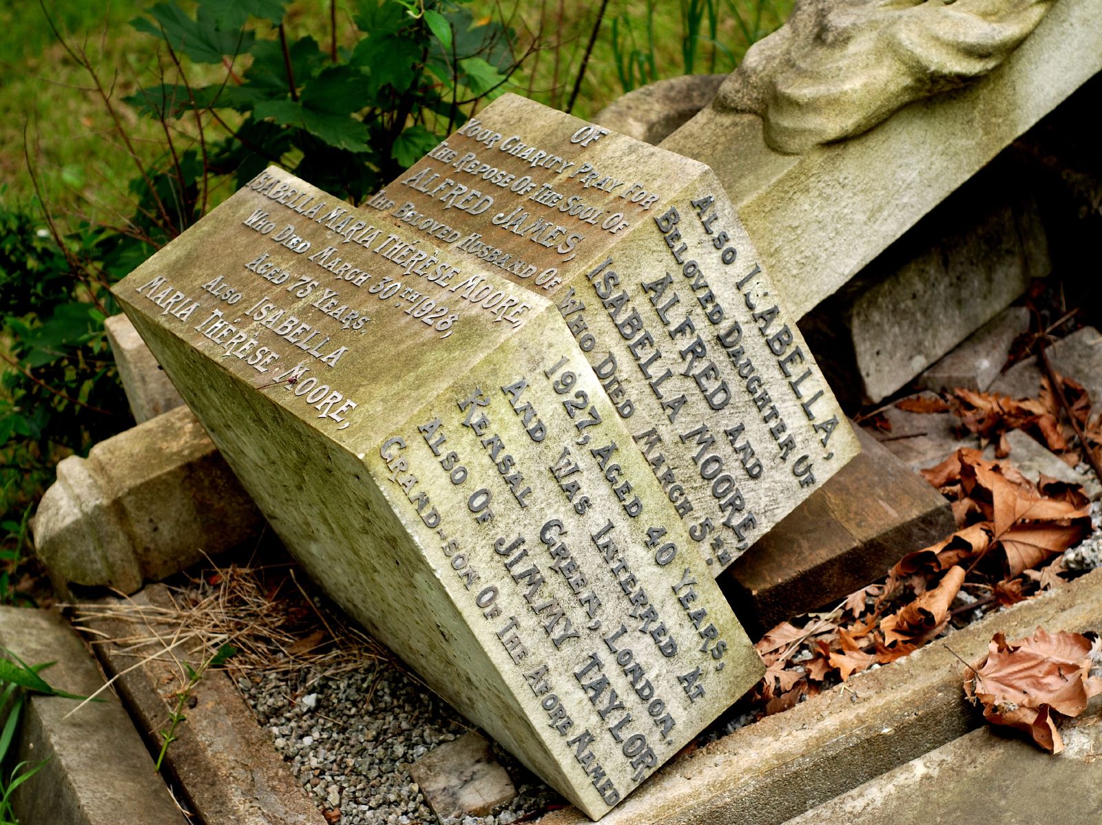 two carved stone sculptures with names sit among leaves