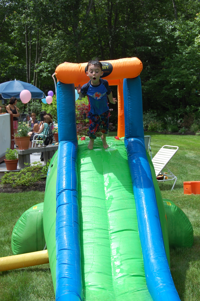 the boy in the blue and green outfit is standing on top of a giant inflatable slide