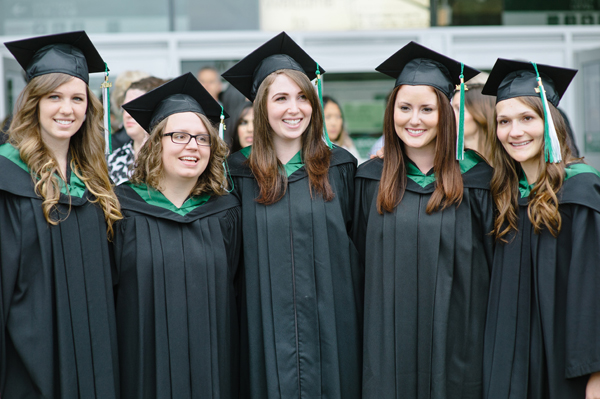 a group of smiling graduates in graduation robes