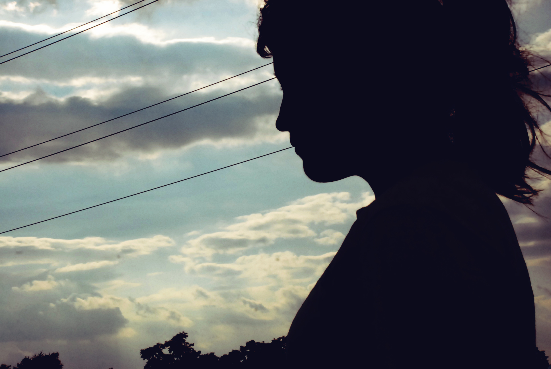 the silhouette of a person against cloudy sky