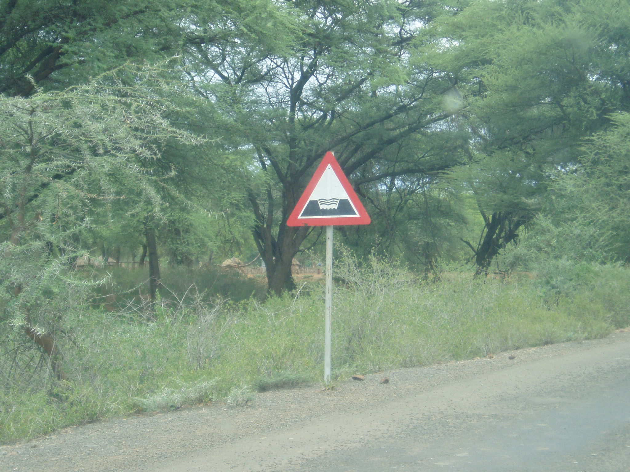 an unusual warning sign stands next to a road