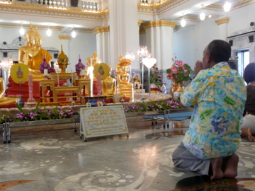 people sitting on stools looking at a shrine