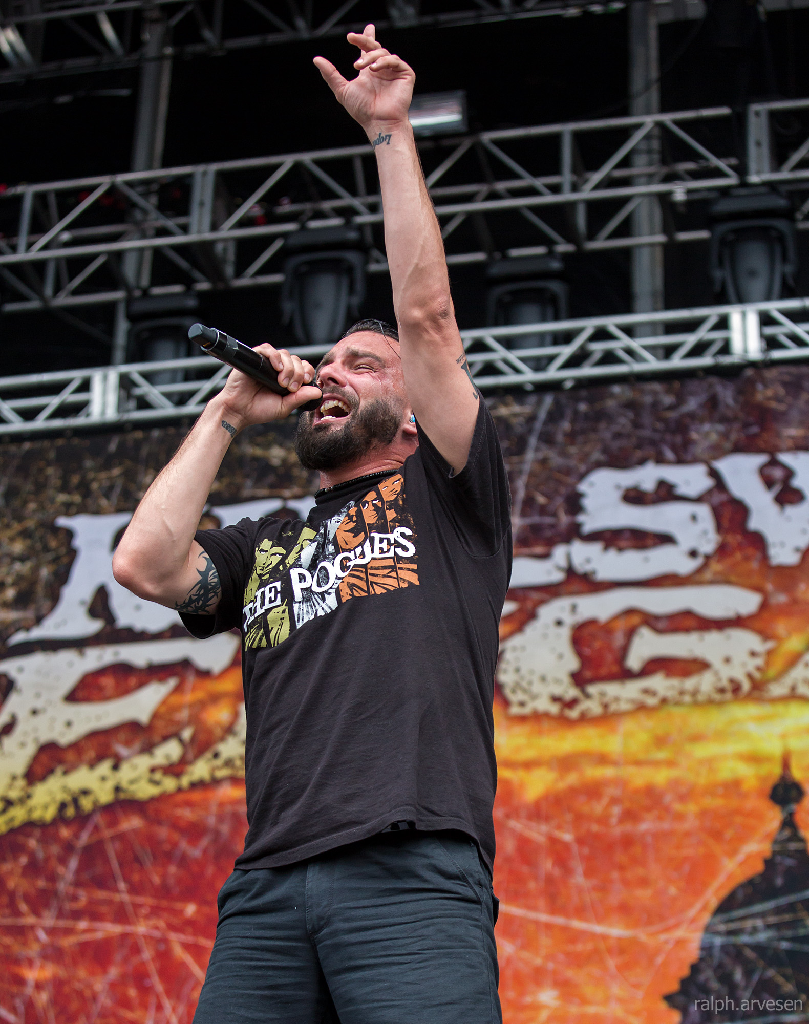 a male with a microphone and hands raised up at a stage