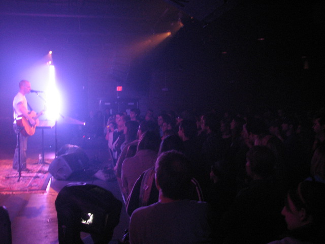 a band plays for a full audience in a dark room
