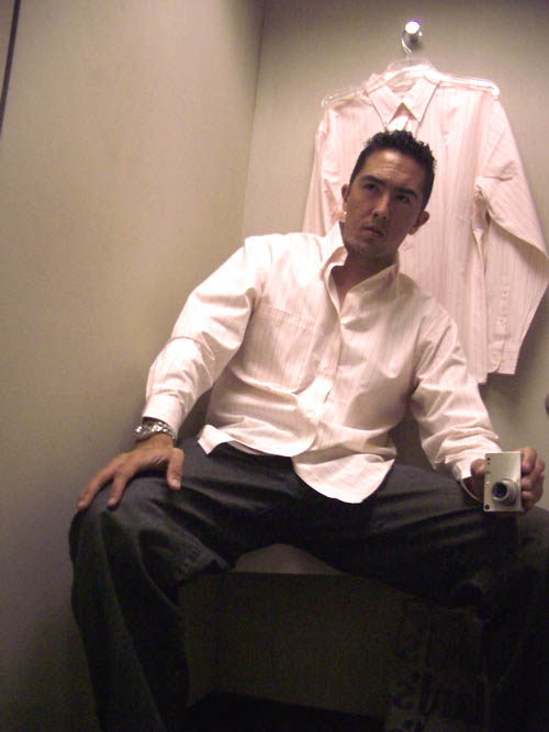 a man sitting on a counter with his hand in the pocket while he holds a coffee mug