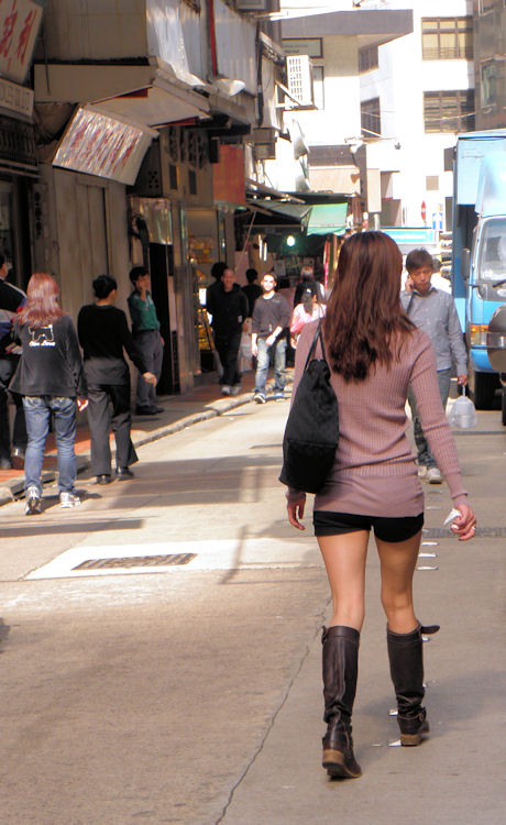 a woman in short shorts is walking down the street