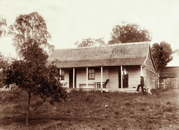 an old pograph with a couple of people in front of a small house