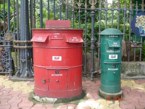 a red trash can sitting next to another green garbage bin