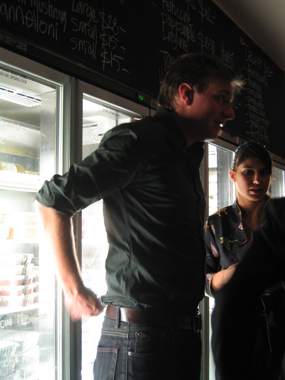 there are two people standing near an open refrigerator