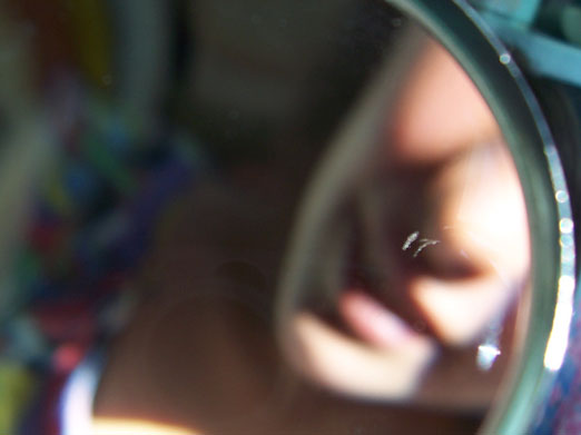 the close up view of a person's face reflected in a round mirror