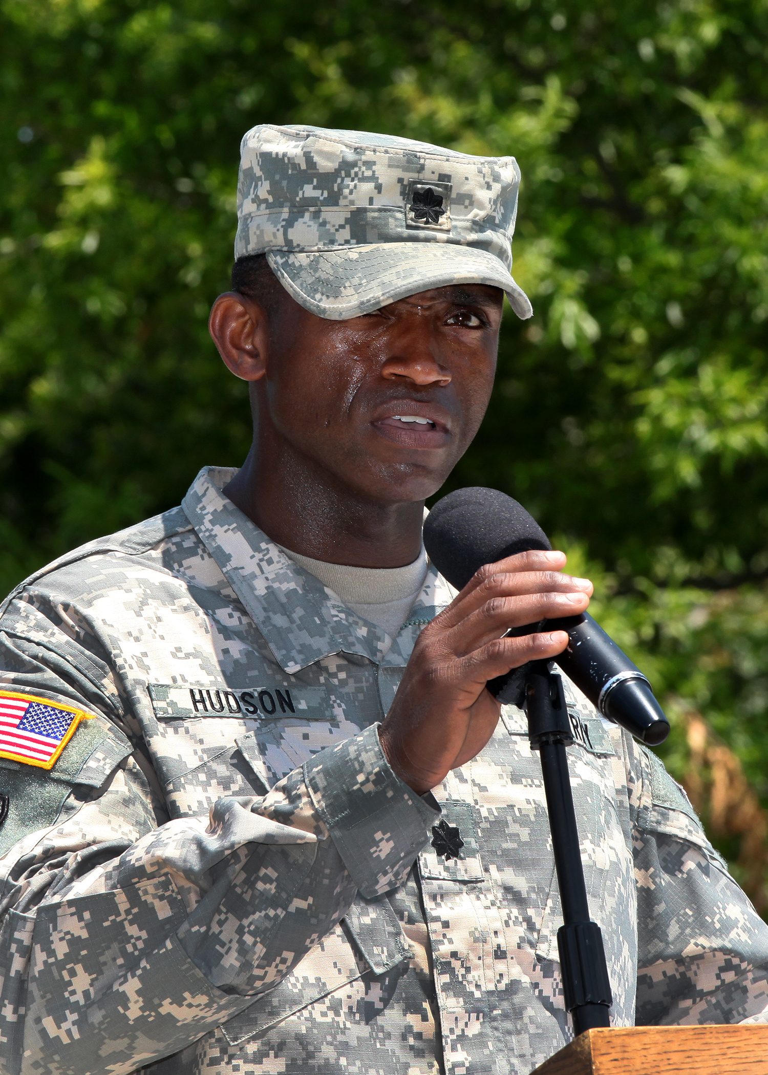 a soldier holding a microphone in front of trees