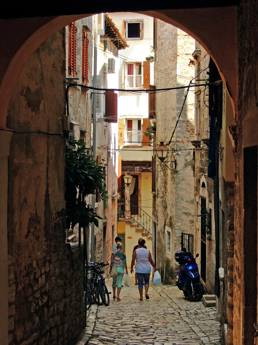 two people are walking down a small stone street
