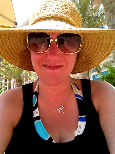a woman wearing a hat and glasses in front of palm trees
