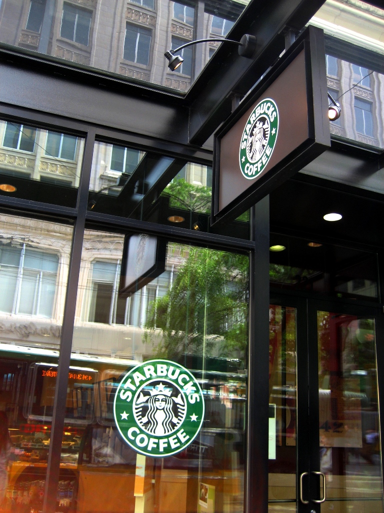 the starbucks logo is posted on the glass front door of the coffee shop