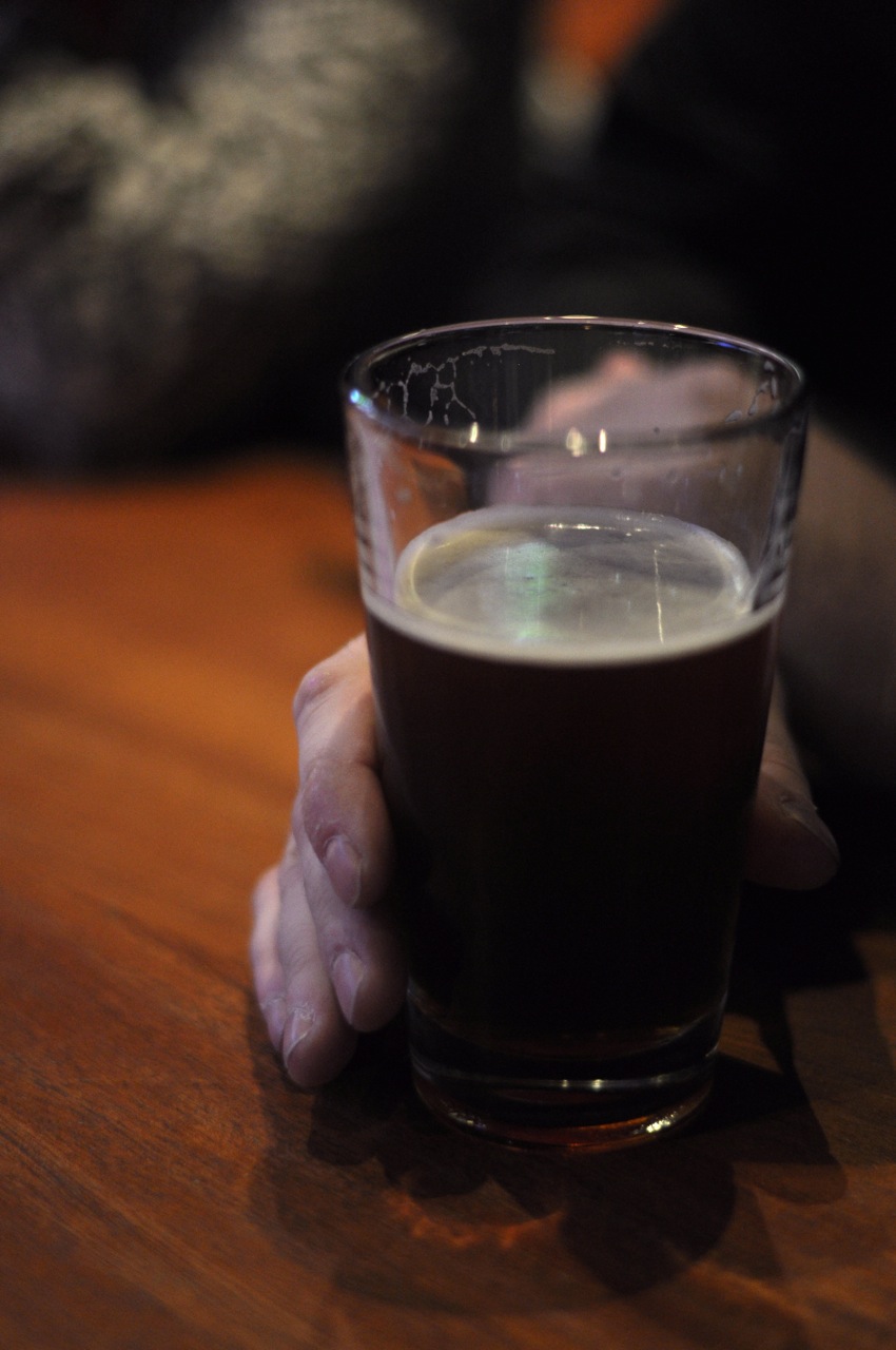 the person is holding a glass with dark ale