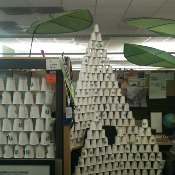 a tree made of cups, surrounded by shelves of white cups