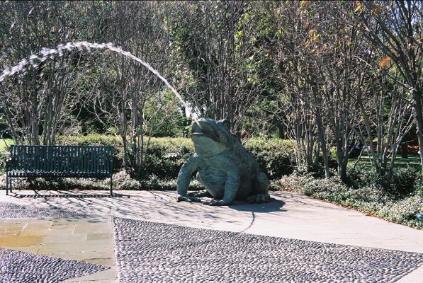 a large statue of an alligator sitting next to a park bench