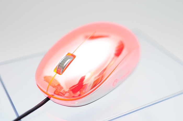 a pink computer mouse that is on top of a glass