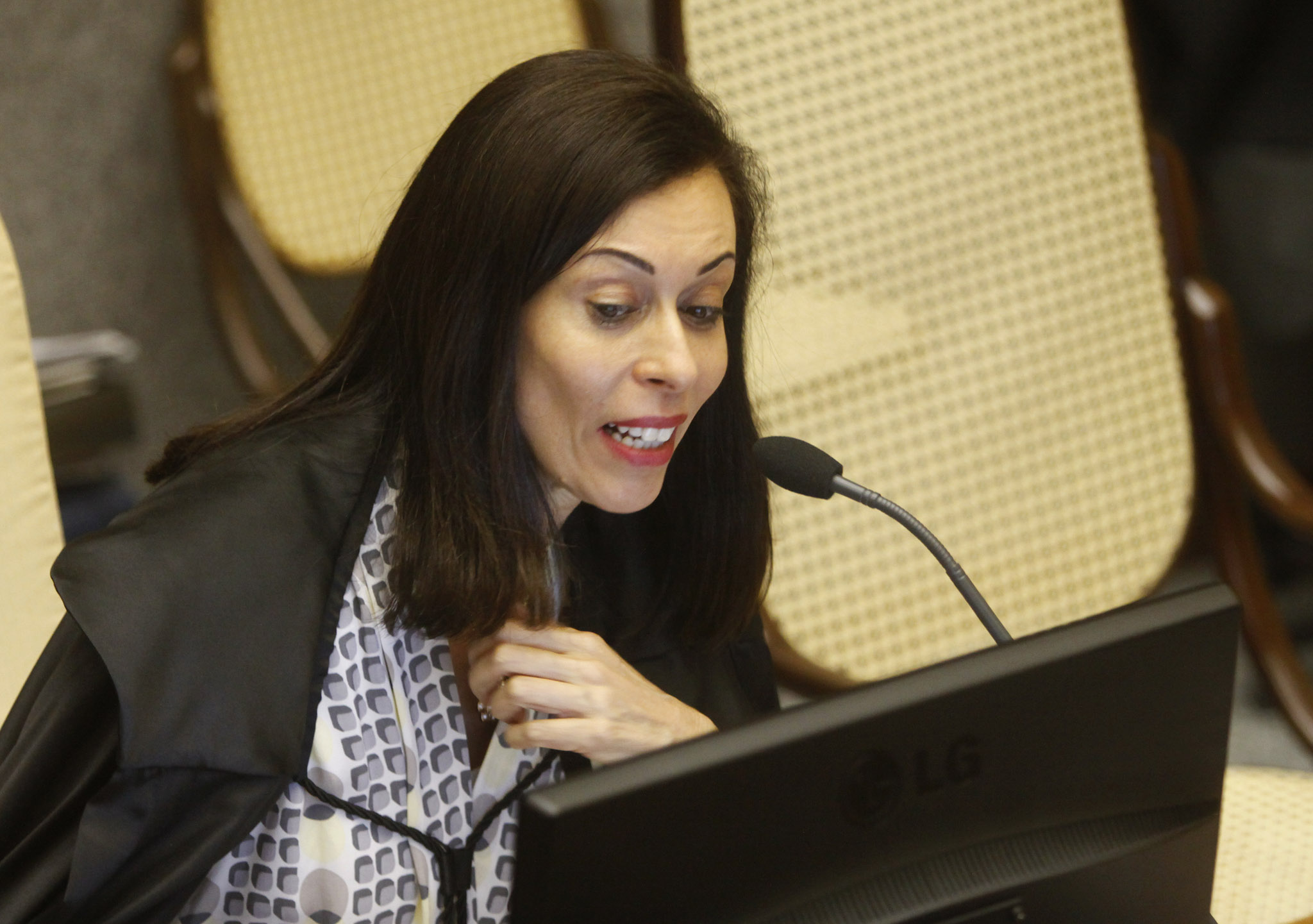 a woman at a podium looking at a laptop screen