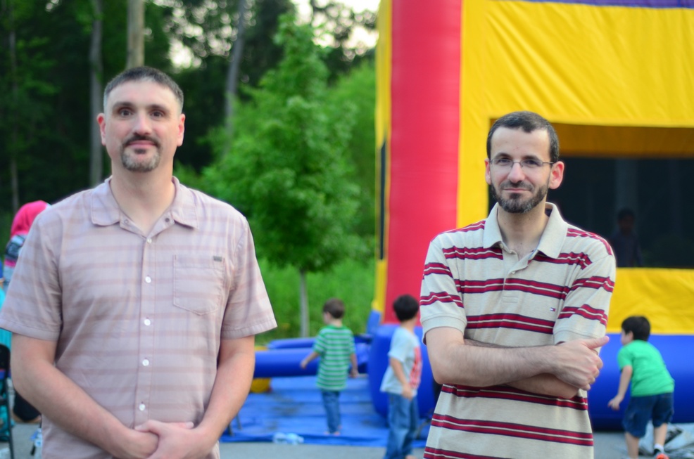 two men standing in front of a large bounce house