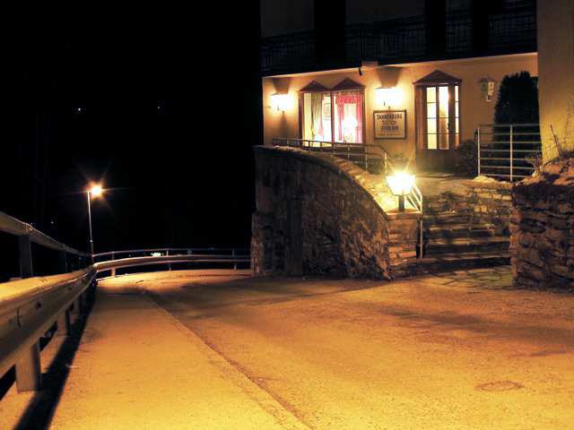 a stone wall and stairway with lights shining on the windows
