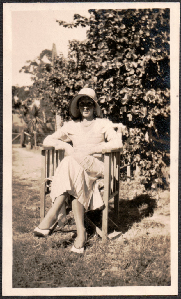 a black and white po of a woman sitting in a wooden chair