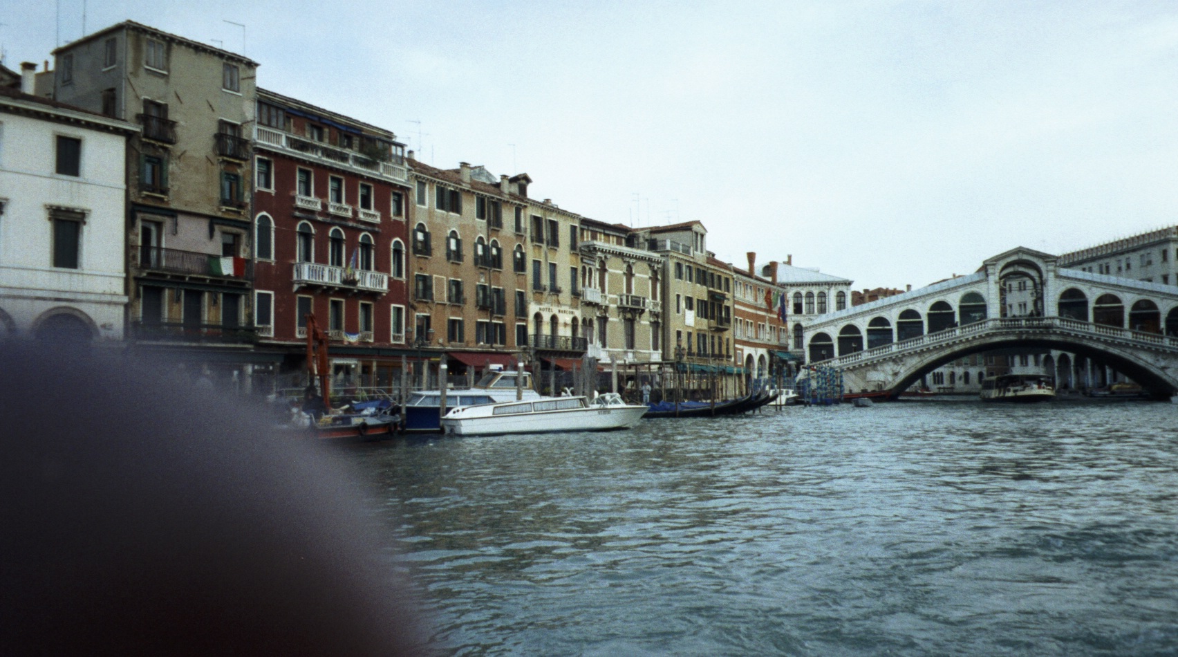 a canal with bridge and boats in the foreground