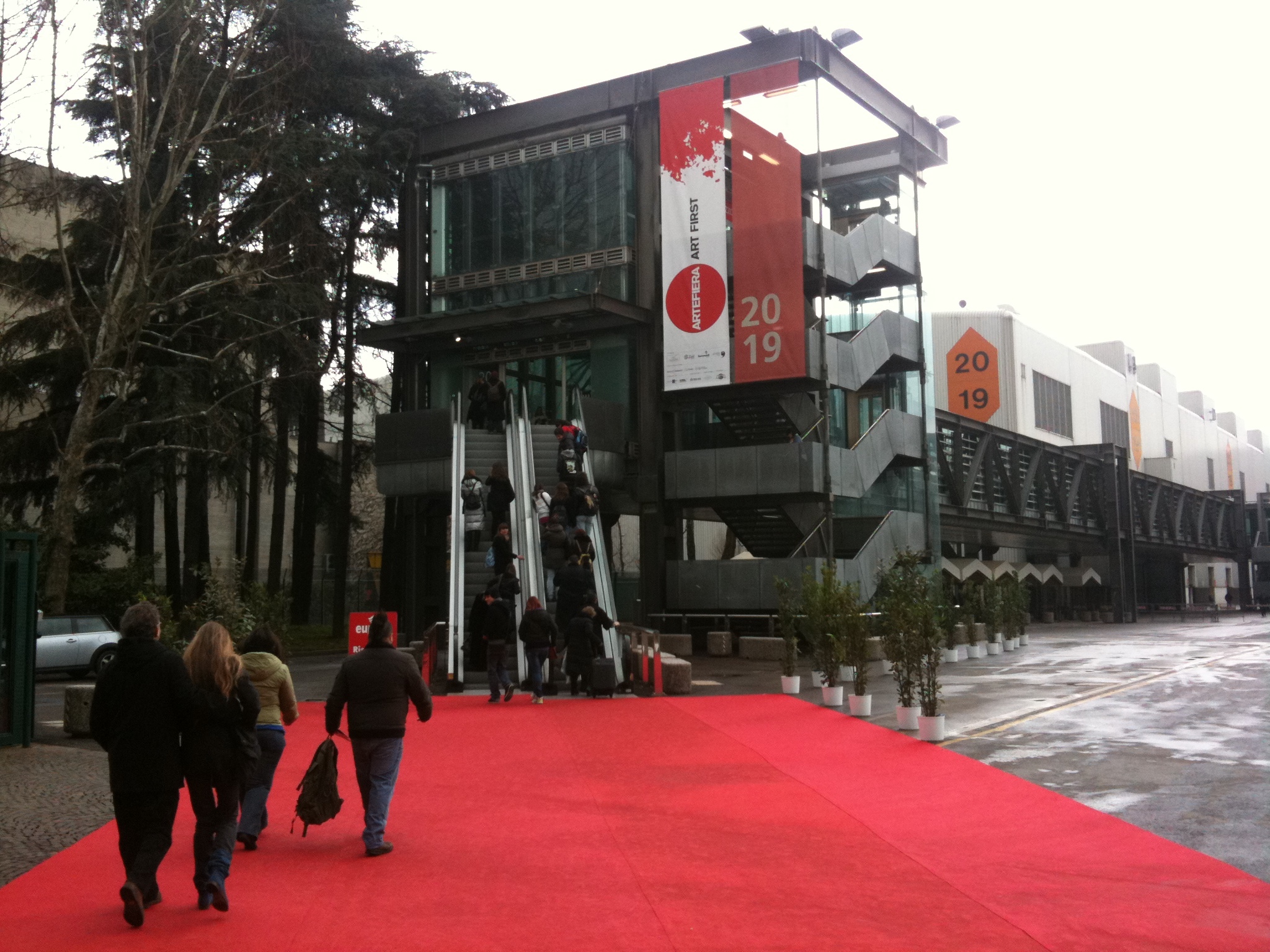 people walking down a red carpeted sidewalk by a building
