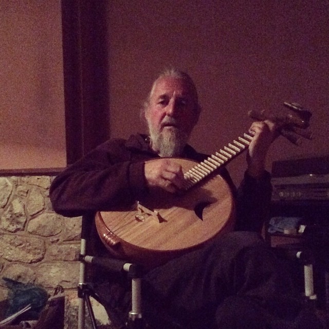 the man is playing a wooden guitar in his living room