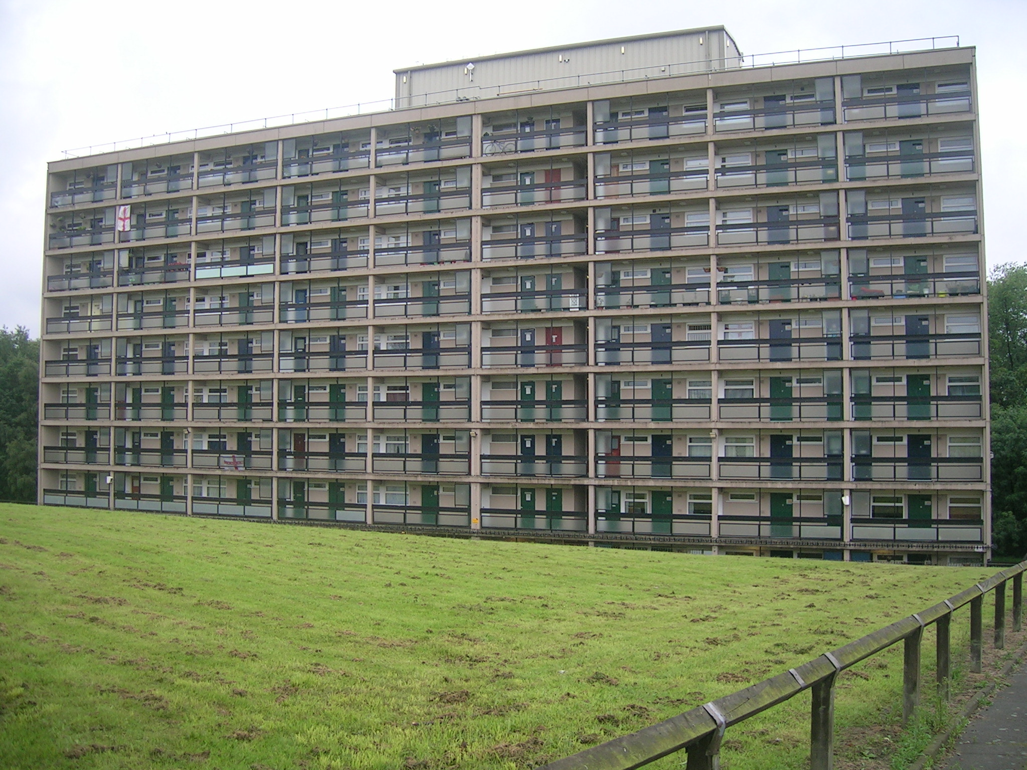 a long building made of many windows that is next to some grass