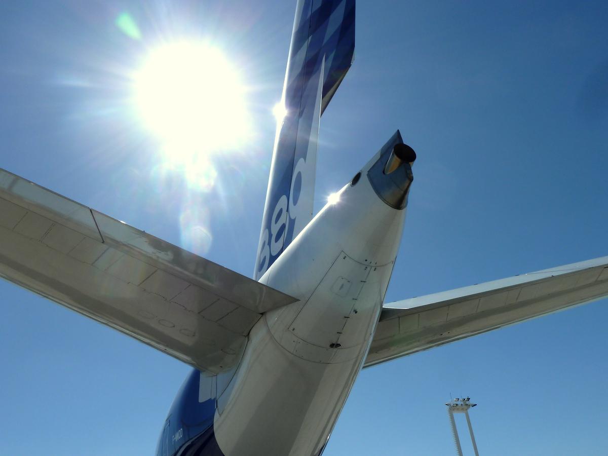 an airplane sitting at the airport with the sun in the sky