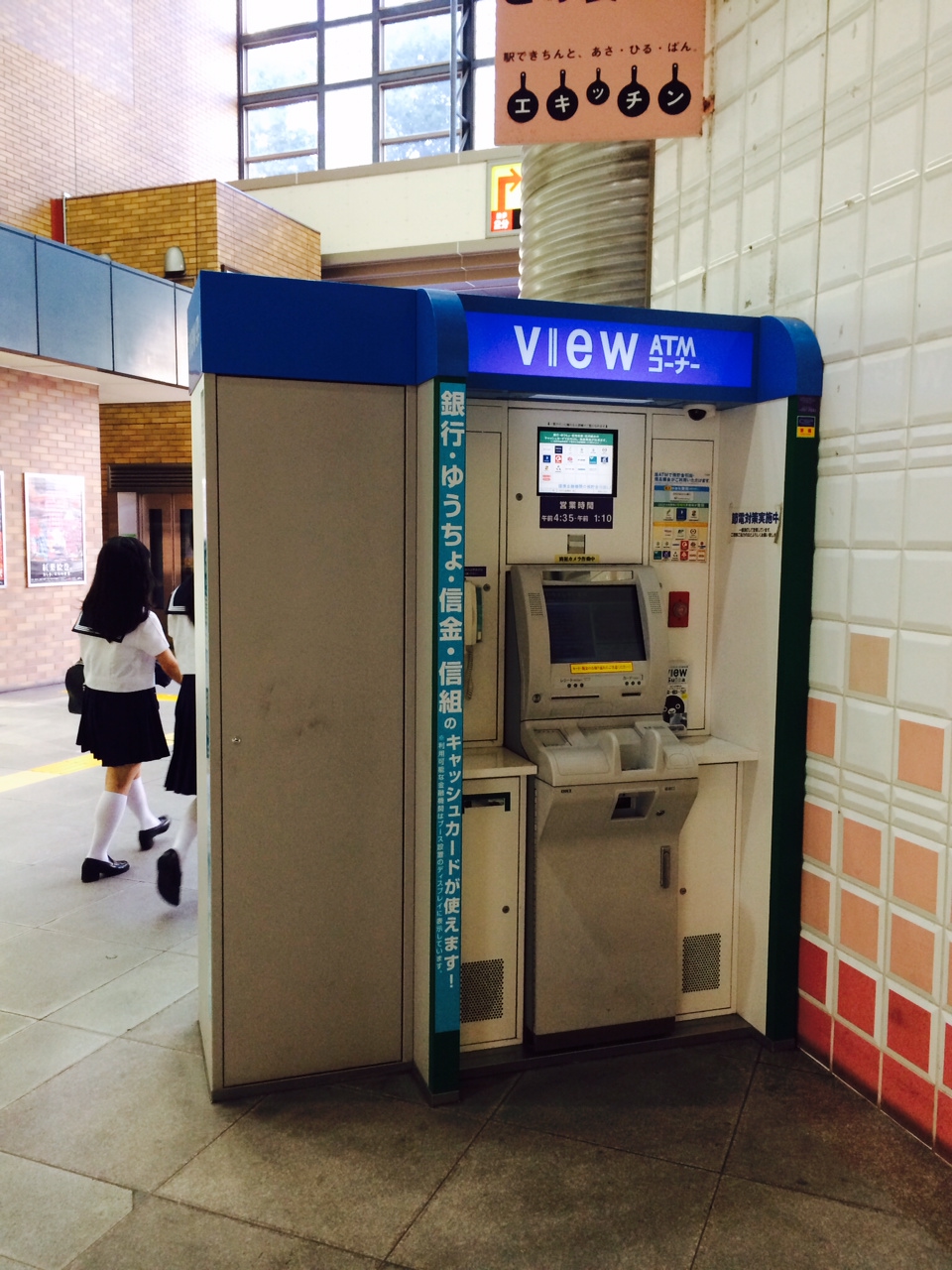 there is a woman walking by a atm