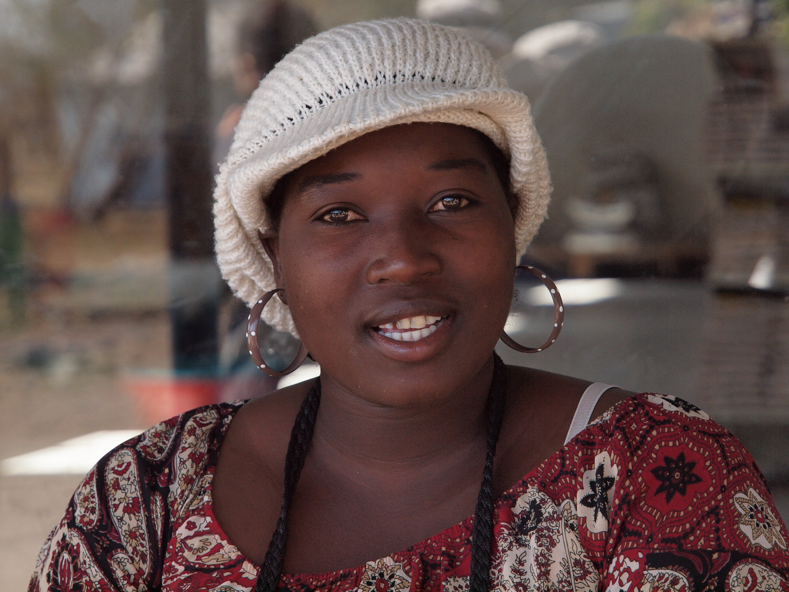 a woman with big hoop earrings on is wearing a hat