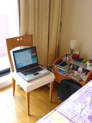 a room with a bed, desk and a laptop computer on it