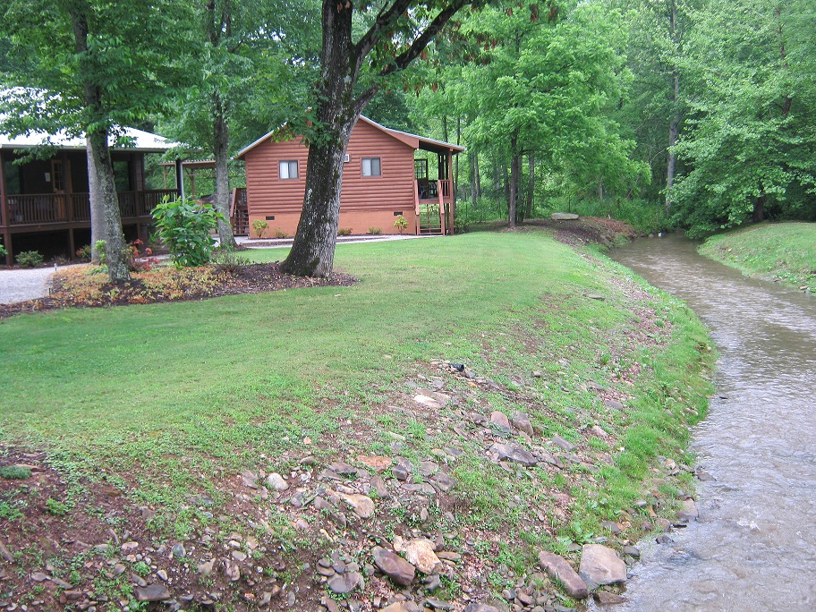 a stream running between two wooden cabins in the woods