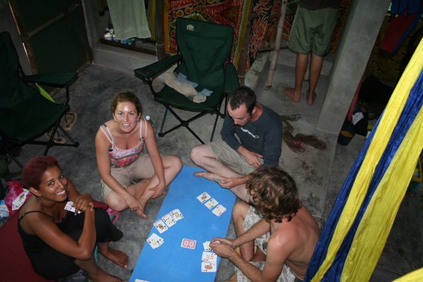 four young adults sitting on the floor playing card games