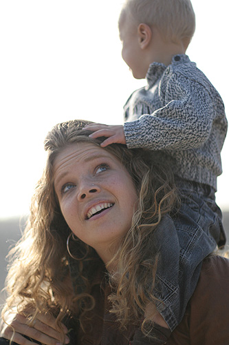 woman in black leather coat and boy on shoulders