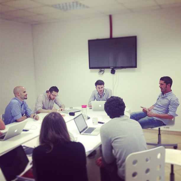 people sitting at tables around laptops in a conference room