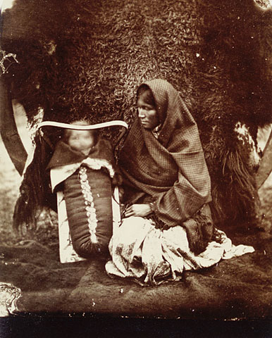 old po of a woman sitting on the ground with a cow
