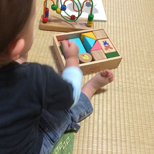 a small child playing with an assortment of wooden toy blocks